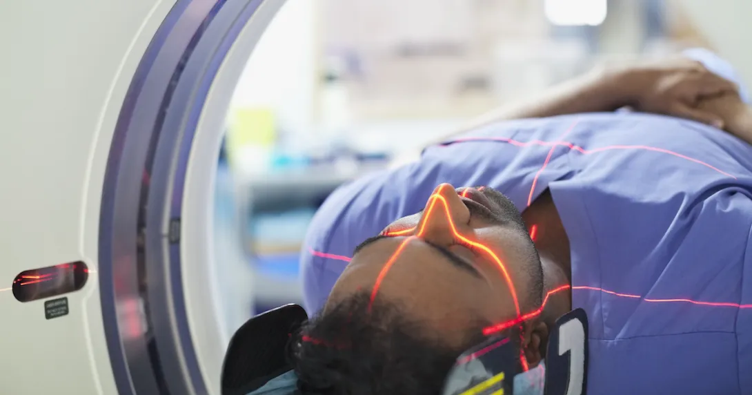 Person being rolled into an imaging machine with red lasers scanning their head
Person being rolled into an imaging machine with red lasers scanning their head