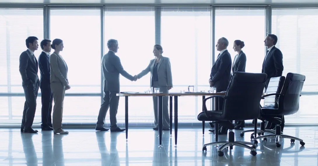 Business officials shake hands to close a deal
