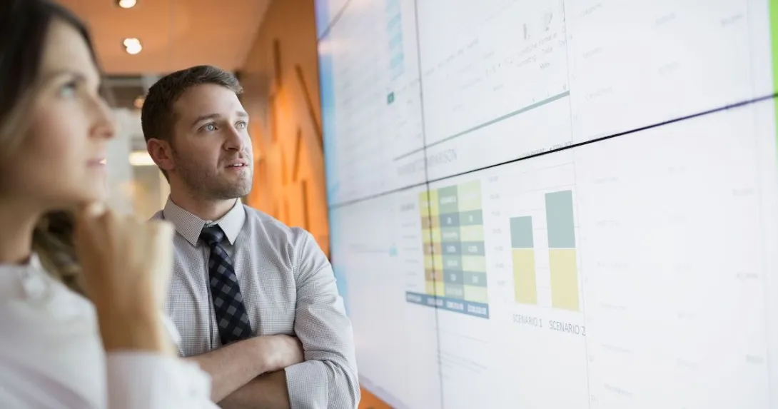 
  Businesspeople looking at financial results on a screen.
