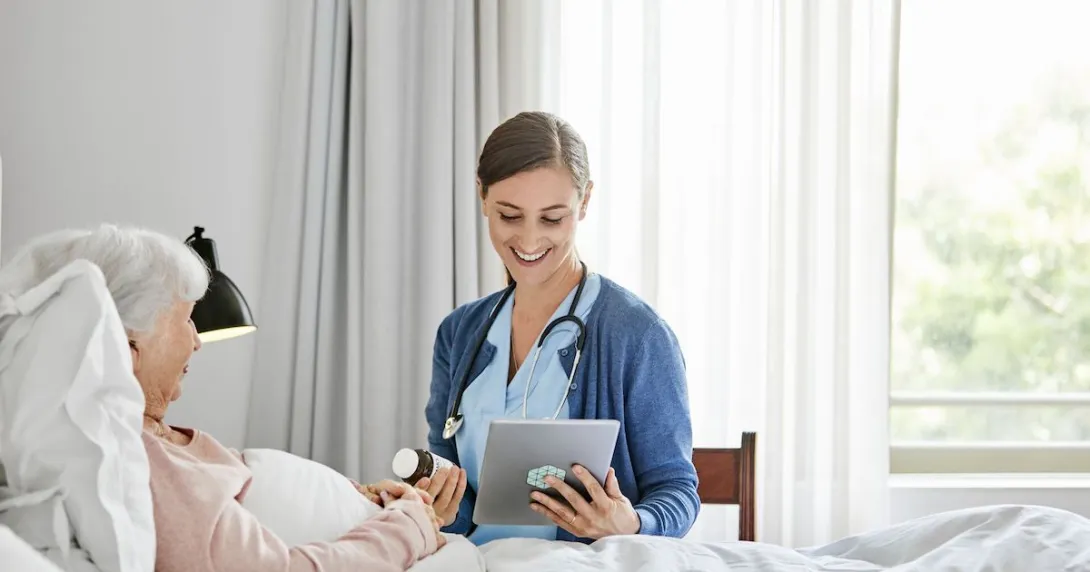 Healthcare provider in a patient's home sitting next to a patient lying in bed Healthcare provider in a patient's home sitting next to a patient lying in bed