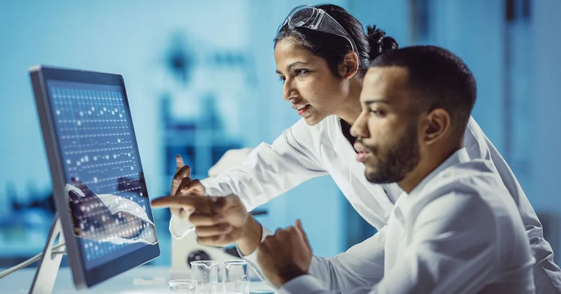 Two scientists sitting at a computer looking at the screen
