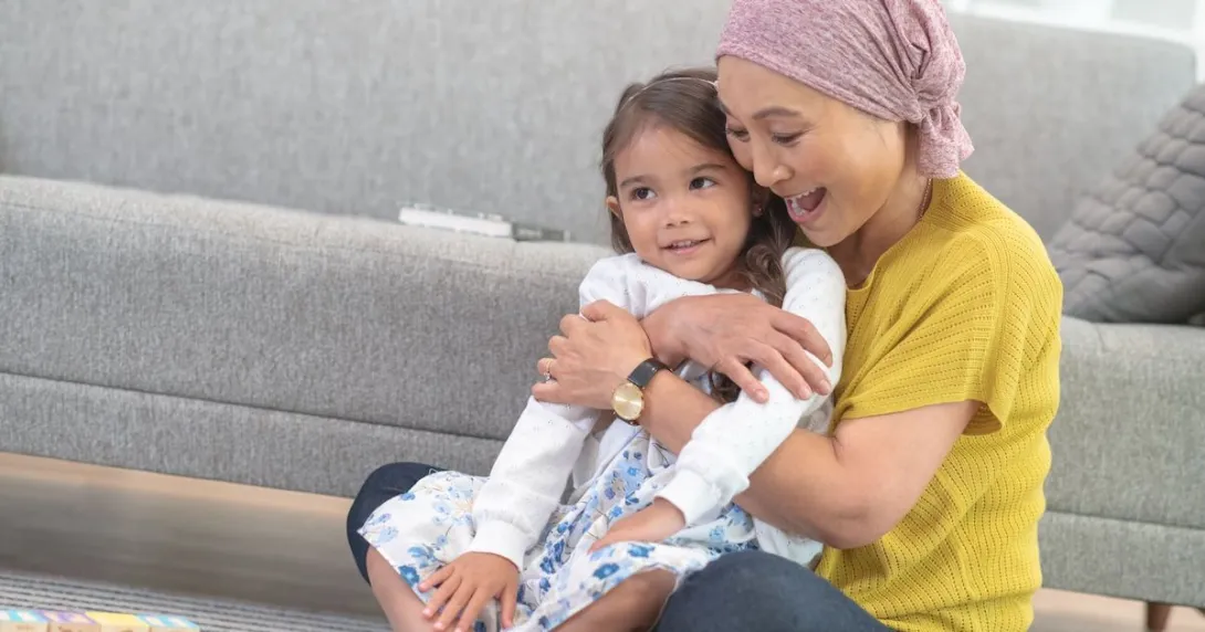 Two people sitting on the floor next to a couch with one wearing a head scarf Two people sitting on the floor next to a couch with one wearing a head scarf
