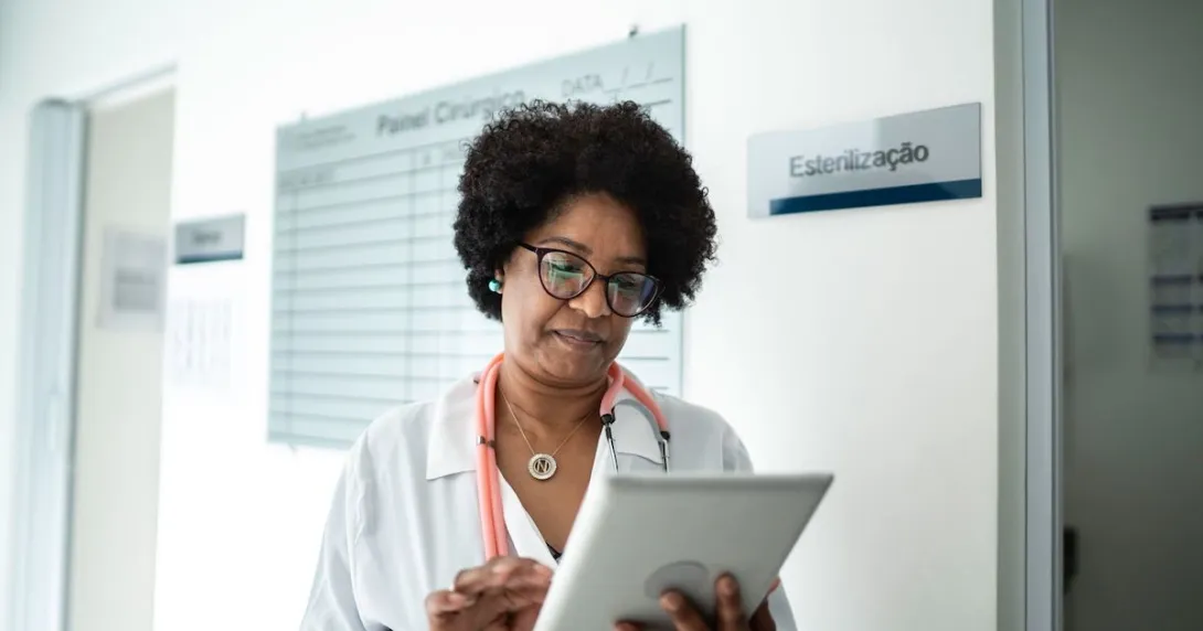 Healthcare provider wearing a lab coat and a stethoscope looking at a tablet
Healthcare provider wearing a lab coat and a stethoscope looking at a tablet
