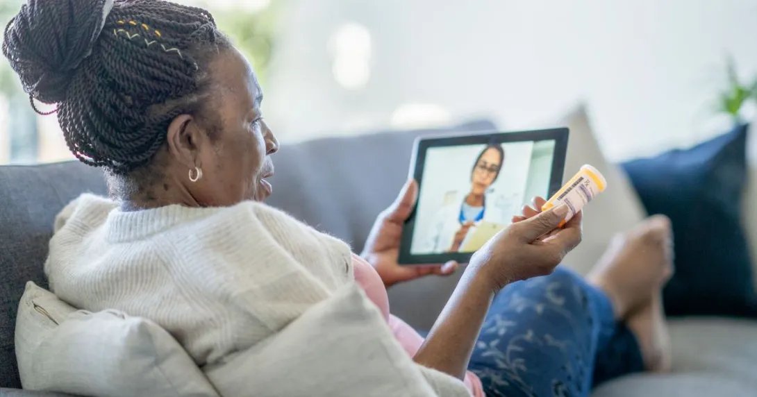 Person sitting on a couch holding a tablet on their lap with a healthcare professional on the screen
Person sitting on a couch holding a tablet on their lap with a healthcare professional on the screen