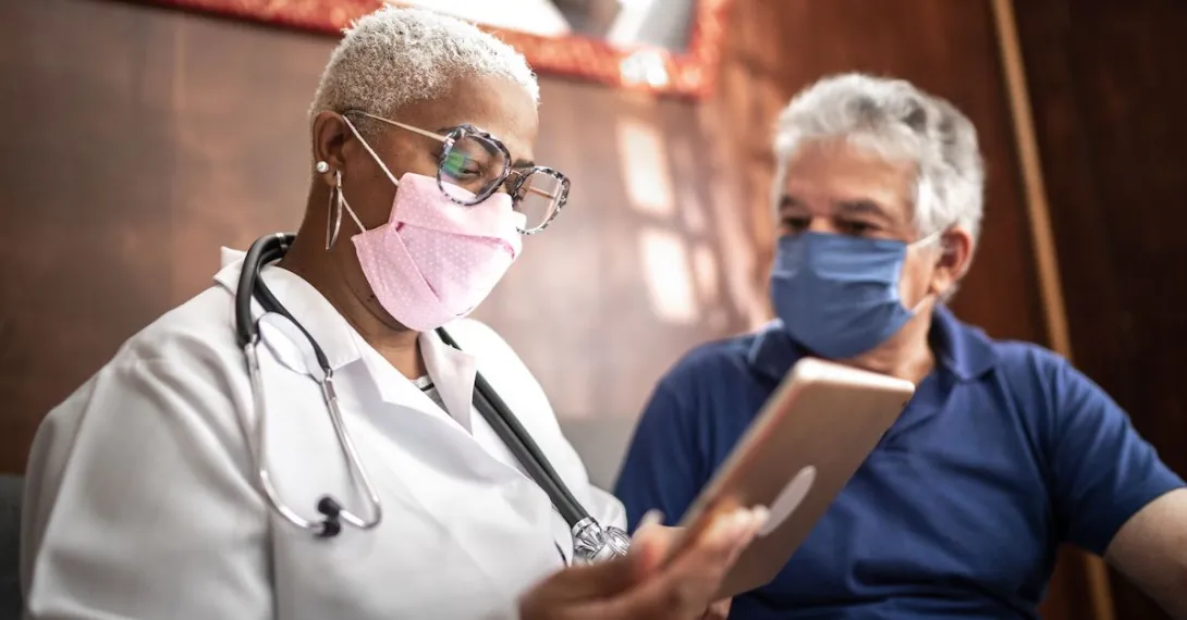 Doctor talking to senior male patient in a home visit