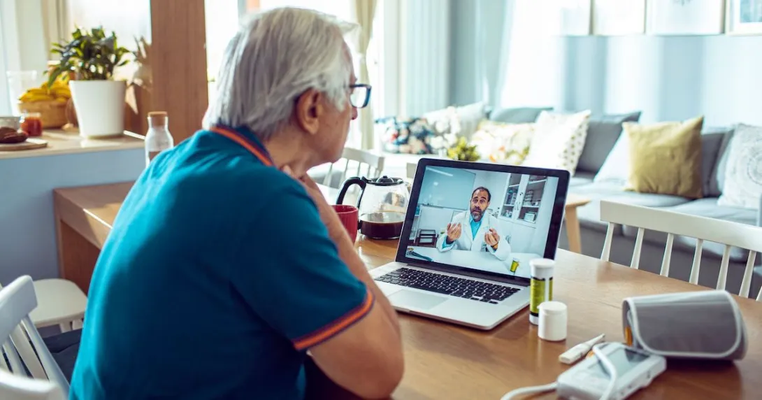 A man talking to a doctor via a laptop with connected devices like a blood pressure cuff and a thermometer A man talking to a doctor via a laptop with connected devices like a blood pressure cuff and a thermometer